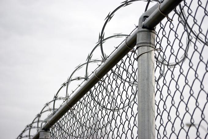 A chain link fence with barbed wire on top.