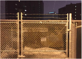 A fence with barbed wire and some buildings in the background