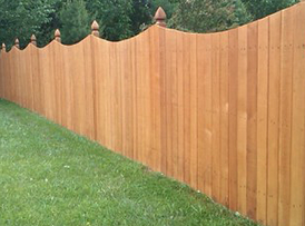 A wooden fence with grass in the foreground.